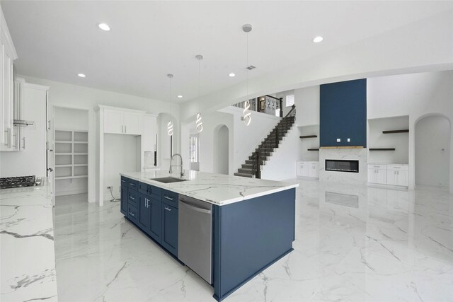 kitchen featuring white cabinetry, decorative light fixtures, dishwasher, sink, and a center island with sink