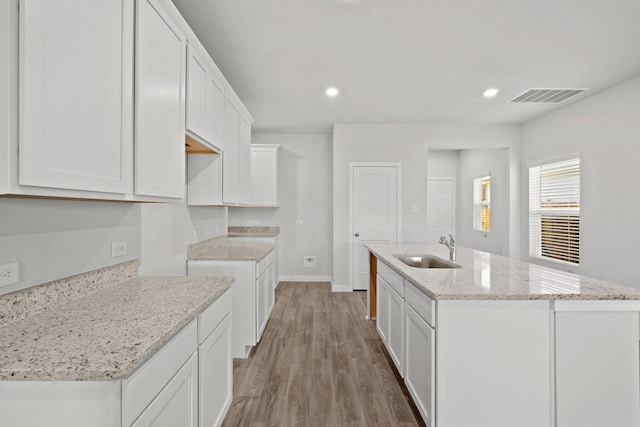 kitchen featuring white cabinets, sink, and an island with sink