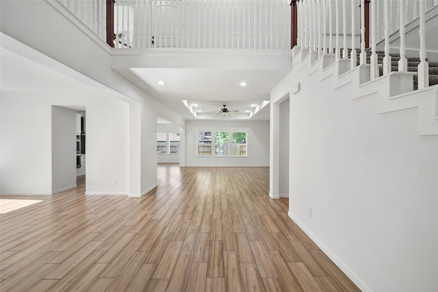 interior space with ceiling fan, light wood-type flooring, and a high ceiling