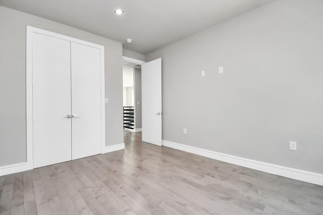 unfurnished bedroom featuring light wood-type flooring and a closet