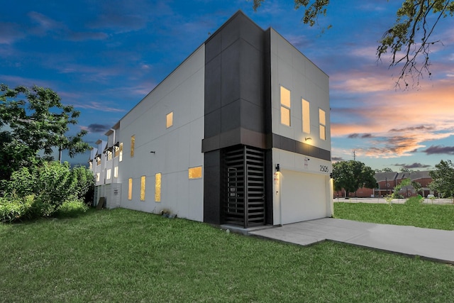 property exterior at dusk featuring a garage and a lawn