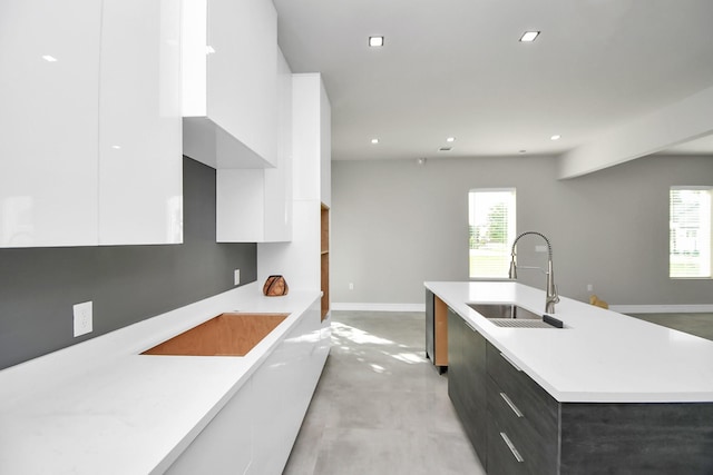 kitchen with white cabinetry, sink, and a center island with sink