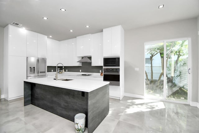 kitchen featuring white cabinetry, sink, black appliances, and a center island with sink