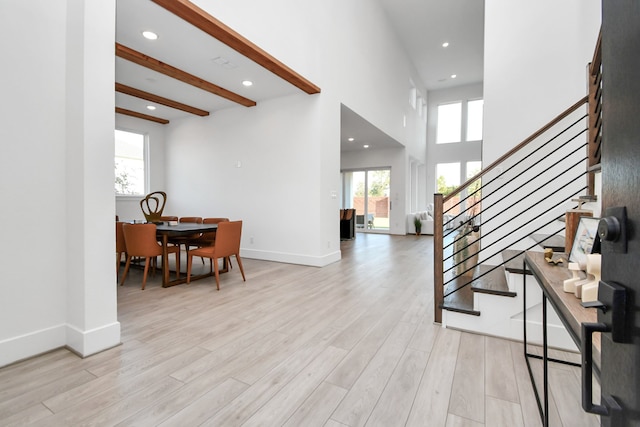 entrance foyer with a high ceiling, light hardwood / wood-style floors, and beamed ceiling