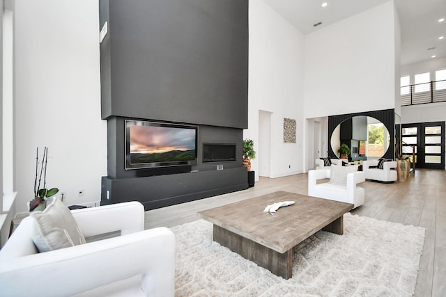 living room with hardwood / wood-style flooring and a towering ceiling