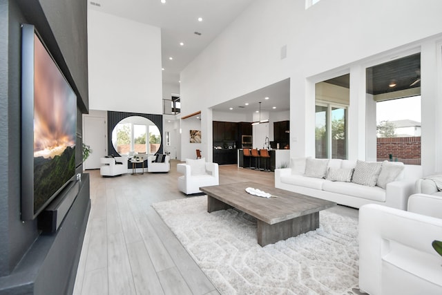 living room with a towering ceiling and light wood-type flooring