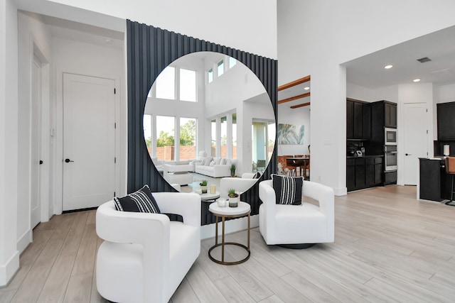 living room with a towering ceiling and light hardwood / wood-style flooring