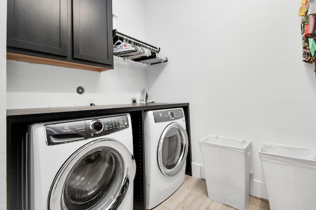 laundry area with separate washer and dryer, light hardwood / wood-style flooring, and cabinets