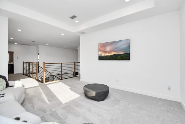 carpeted living room with a tray ceiling