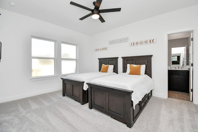 bedroom featuring light carpet, sink, ensuite bathroom, and ceiling fan