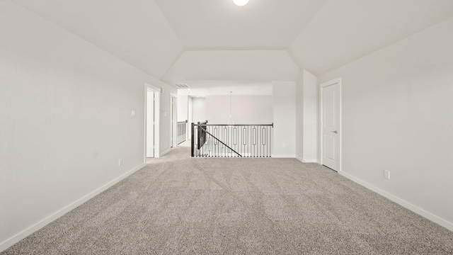 carpeted spare room with vaulted ceiling