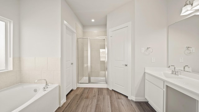 bathroom with hardwood / wood-style floors, vanity, and independent shower and bath