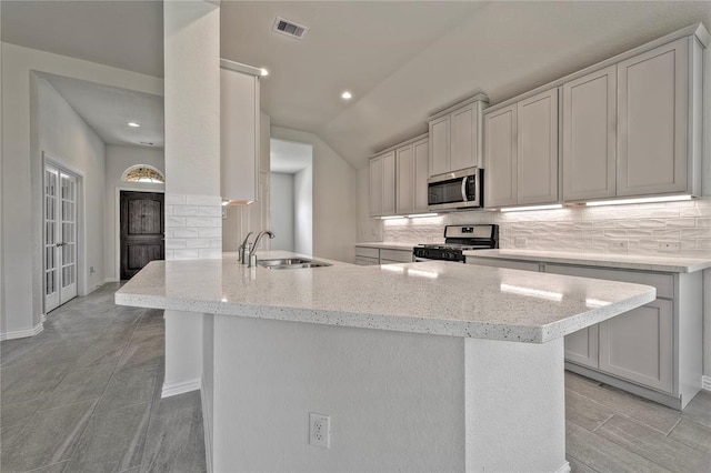 kitchen with appliances with stainless steel finishes, light stone counters, decorative backsplash, and sink