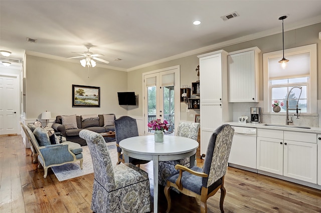 dining room with a wealth of natural light, crown molding, ceiling fan, and light wood-type flooring