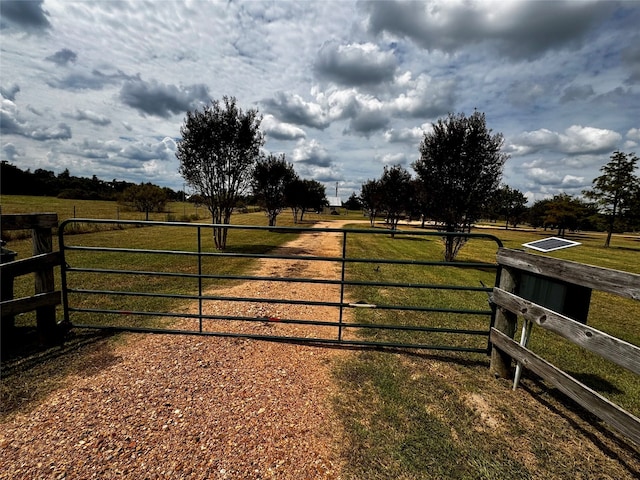 view of gate featuring a lawn and a rural view