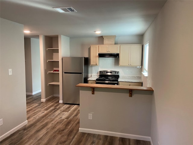 kitchen featuring dark wood-style flooring, visible vents, decorative backsplash, appliances with stainless steel finishes, and under cabinet range hood