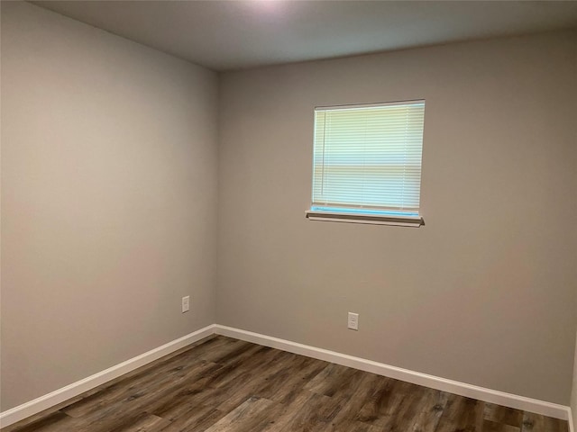 empty room with dark wood-style floors and baseboards