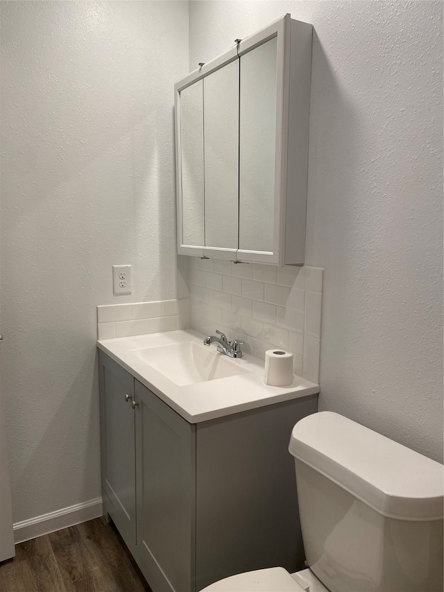 bathroom with wood-type flooring, toilet, tasteful backsplash, and vanity