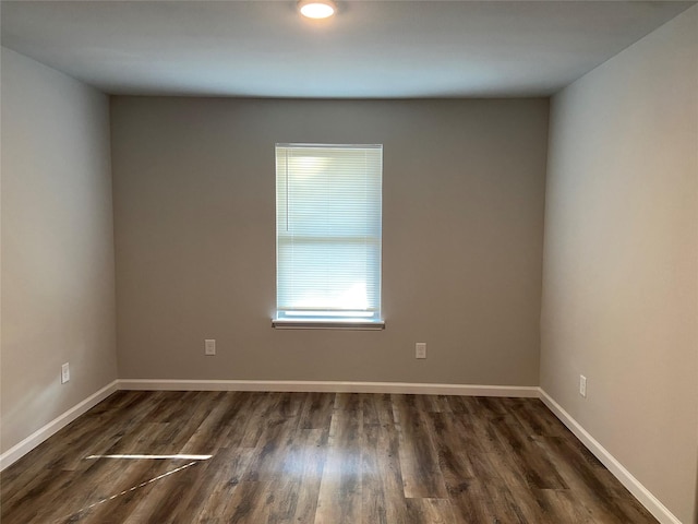 empty room with dark wood-style flooring and baseboards