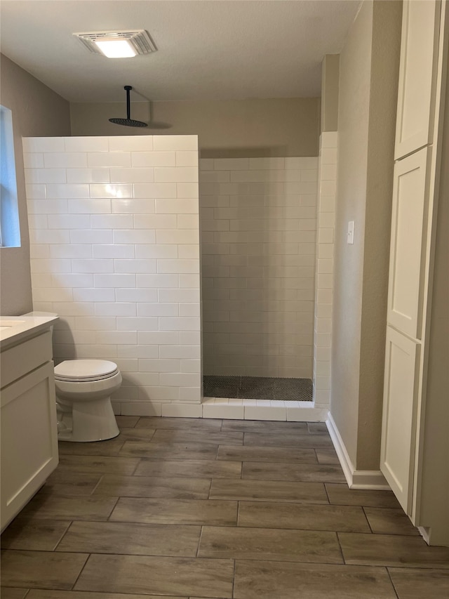 bathroom with tiled shower, toilet, tile walls, and vanity