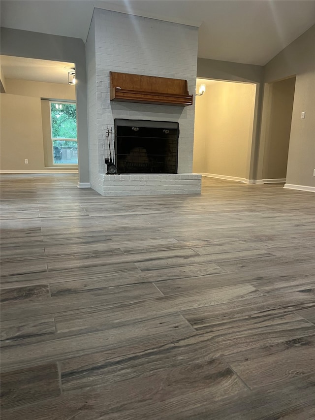 unfurnished living room with lofted ceiling, dark wood-type flooring, and a fireplace