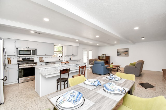 dining space with beamed ceiling, sink, and a textured ceiling