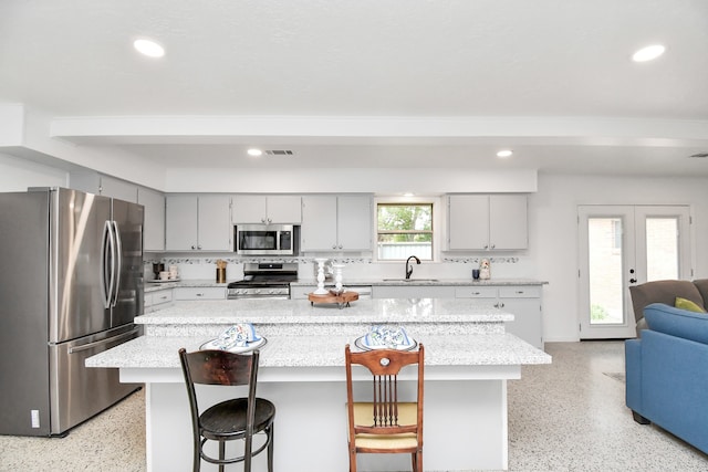 kitchen featuring a breakfast bar area, a kitchen island, sink, french doors, and stainless steel appliances