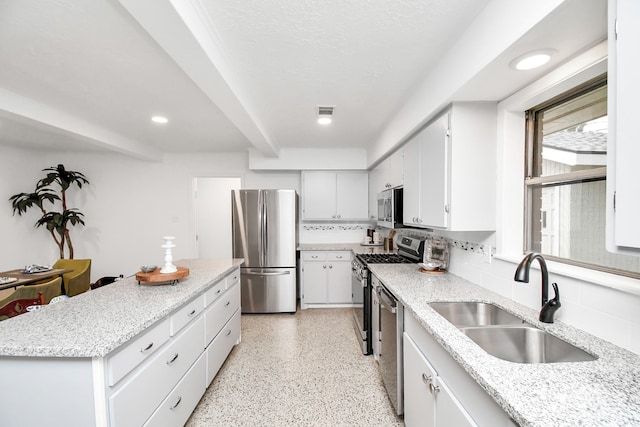 kitchen with decorative backsplash, sink, light stone countertops, white cabinetry, and appliances with stainless steel finishes