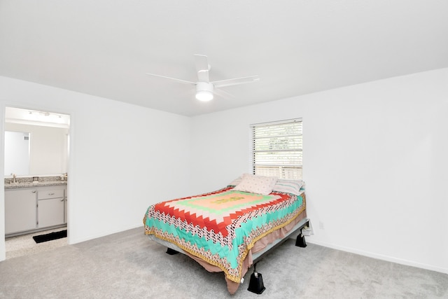 bedroom with ceiling fan, ensuite bath, sink, and light colored carpet