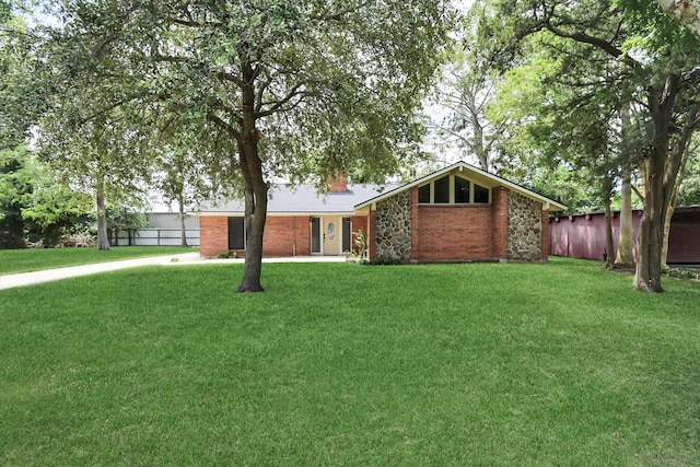 view of front of property with brick siding, a chimney, a front yard, and fence