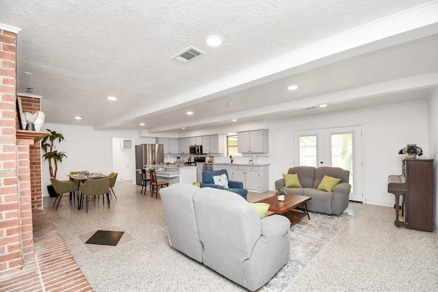 living room featuring french doors, beam ceiling, and a textured ceiling