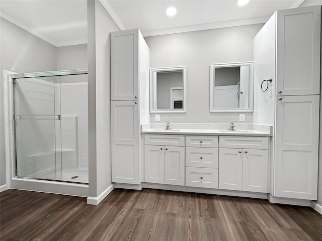 bathroom featuring crown molding, hardwood / wood-style floors, double sink vanity, and walk in shower