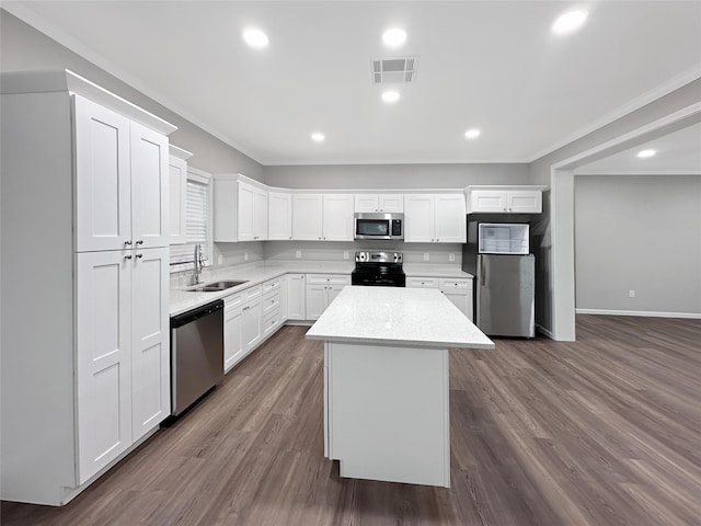 kitchen with a center island, stainless steel appliances, sink, dark wood-type flooring, and ornamental molding