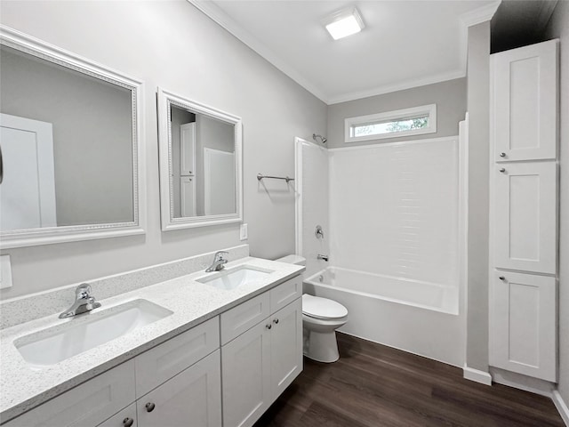 full bathroom with double sink vanity, wood-type flooring, toilet, ornamental molding, and washtub / shower combination