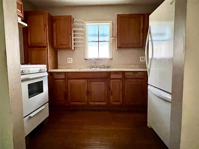 kitchen with dark wood-type flooring, white appliances, and sink