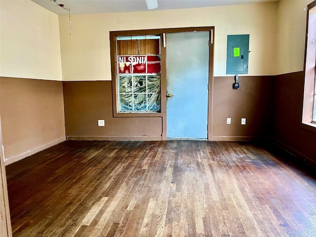 spare room featuring wood-type flooring, electric panel, and baseboards