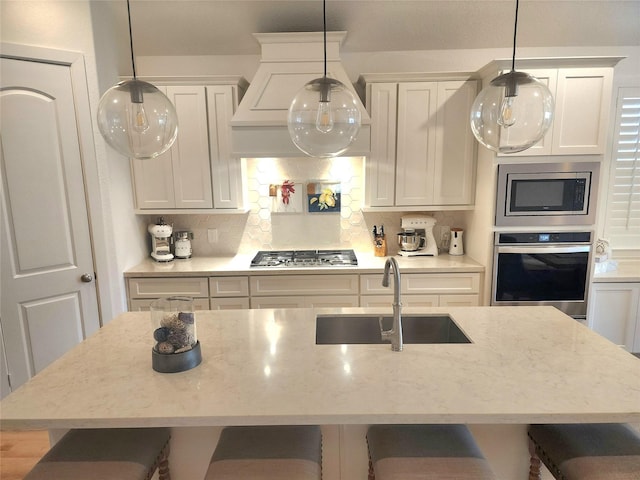 kitchen with a breakfast bar area, backsplash, pendant lighting, a sink, and stainless steel appliances