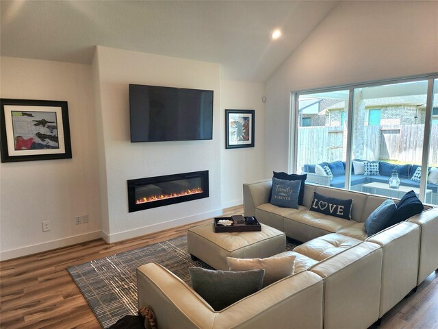 living area with a glass covered fireplace, baseboards, recessed lighting, and wood finished floors