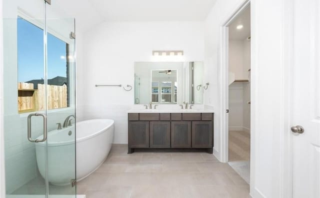 full bath with a sink, tile patterned flooring, a soaking tub, and double vanity