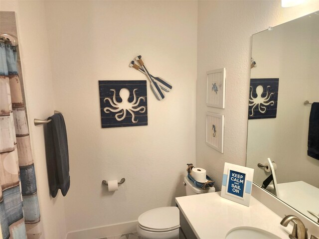 full bath featuring baseboards, vanity, and toilet