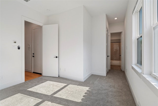 unfurnished bedroom featuring ensuite bathroom and light carpet