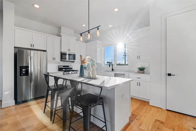 kitchen with a center island, tasteful backsplash, appliances with stainless steel finishes, white cabinets, and light wood-type flooring