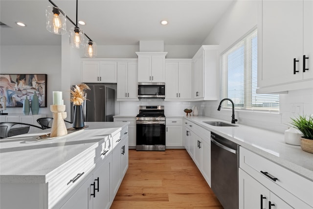 kitchen with appliances with stainless steel finishes, backsplash, sink, light hardwood / wood-style flooring, and white cabinetry