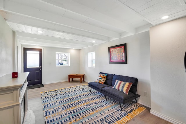 living room featuring beamed ceiling and light hardwood / wood-style floors