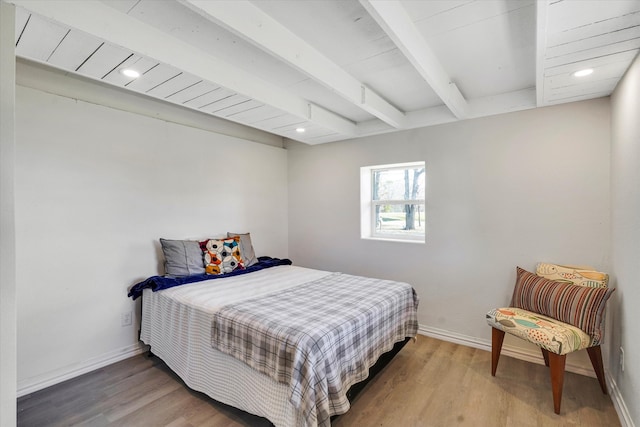 bedroom with beamed ceiling and hardwood / wood-style flooring