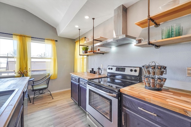 kitchen featuring vaulted ceiling, wood counters, stainless steel range with electric stovetop, wall chimney range hood, and light wood-type flooring