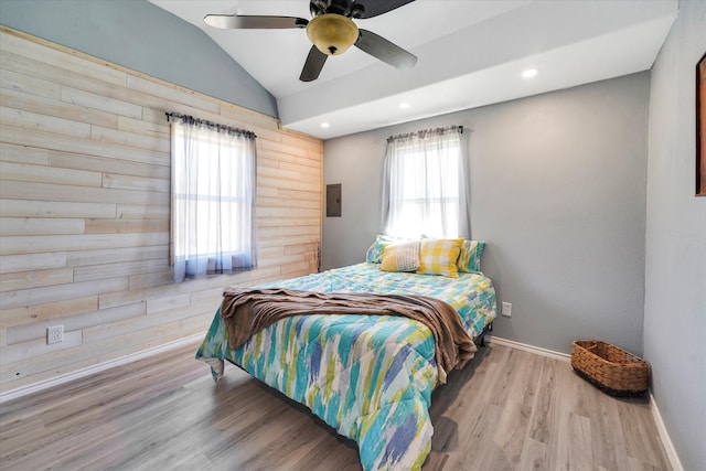 bedroom with lofted ceiling, hardwood / wood-style floors, wood walls, and ceiling fan