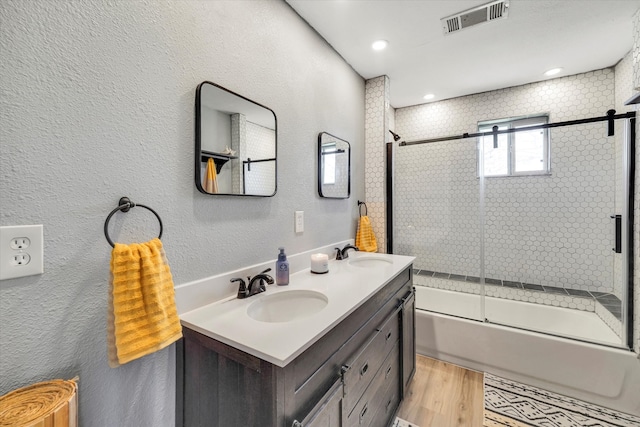 bathroom with wood-type flooring, bath / shower combo with glass door, and vanity