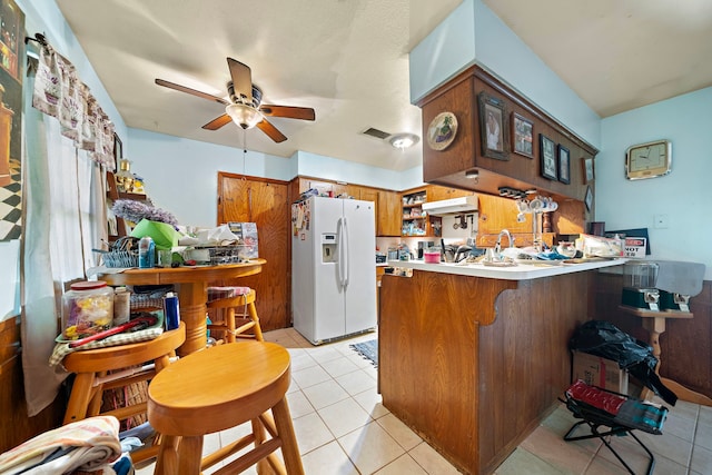 kitchen featuring white refrigerator with ice dispenser, kitchen peninsula, ceiling fan, and light tile patterned flooring