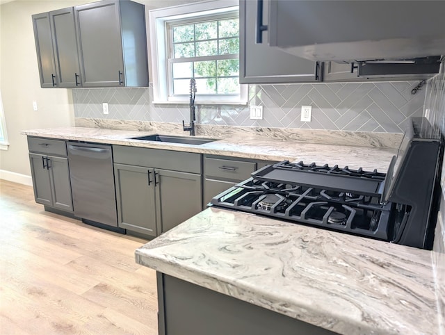 kitchen with decorative backsplash, light wood-type flooring, dishwasher, gray cabinetry, and sink